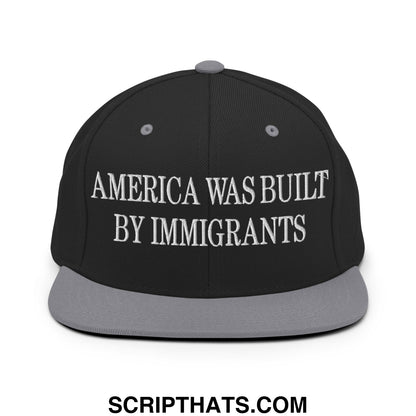 Black snapback cap with gray brim featuring white embroidered text america was built by immigrants