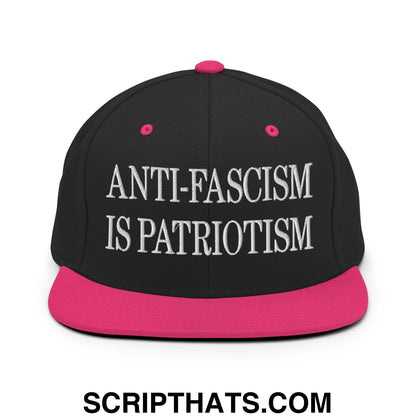 Black snapback hat with vibrant pink brim and button featuring anti-fascism is patriotism embroidered text