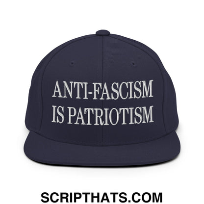Navy blue snapback cap with white embroidered anti-fascism is patriotism text and flat bill brim design