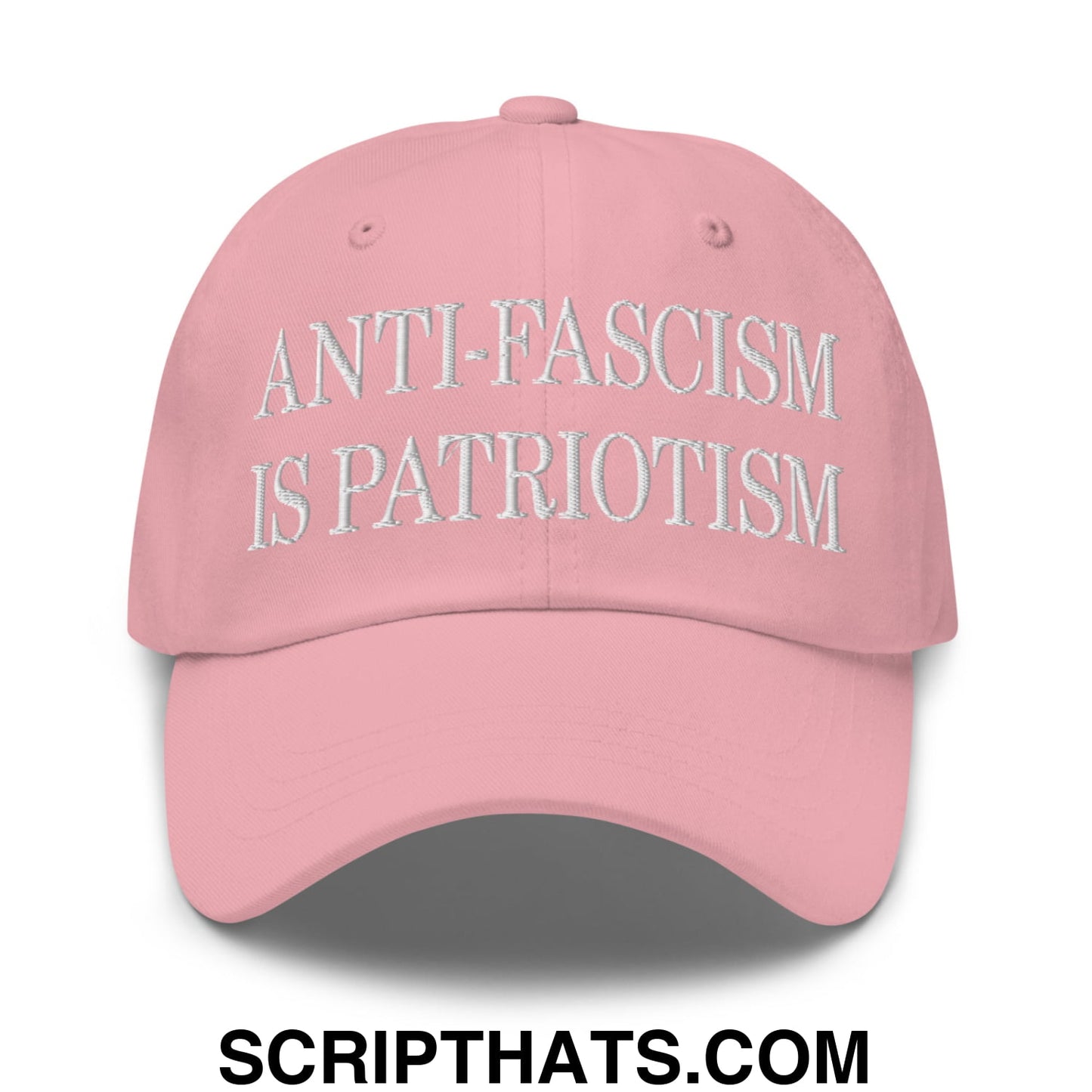 A soft pink unstructured dad hat with white embroidered text reading anti-fascism is patriotism
