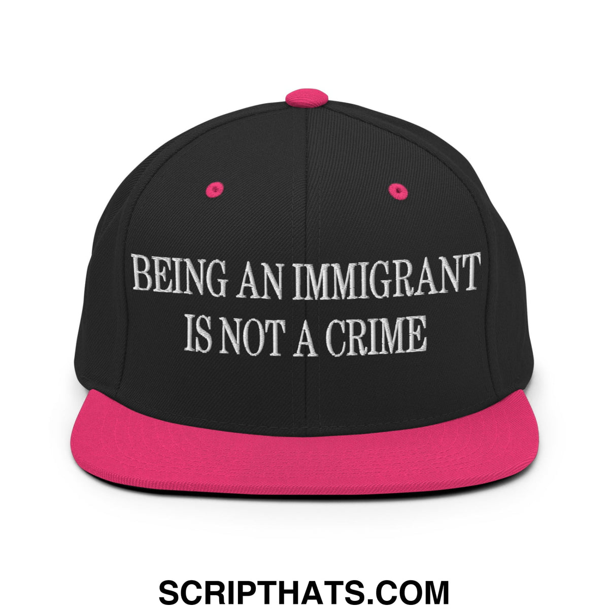Black snapback cap with vibrant pink brim and button featuring white embroidered text being an immigrant is not a crime
