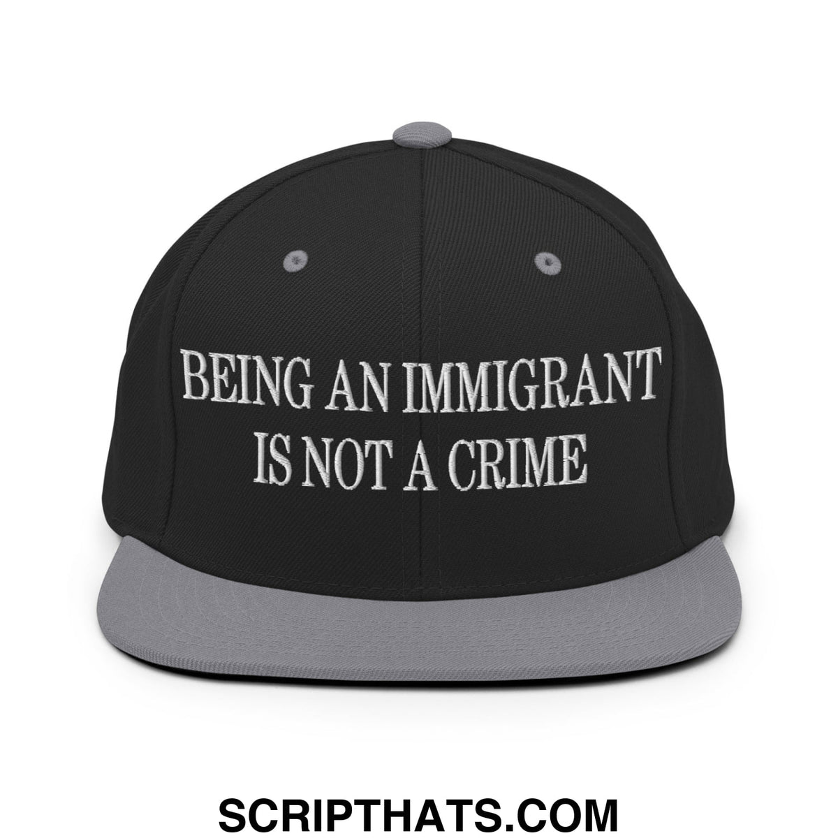 Black snapback hat with gray brim featuring white embroidered text being an immigrant is not a crime
