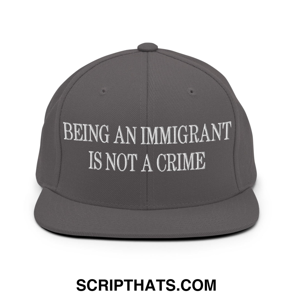 Gray snapback hat with white embroidered text reading being an immigrant is not a crime on the front panel
