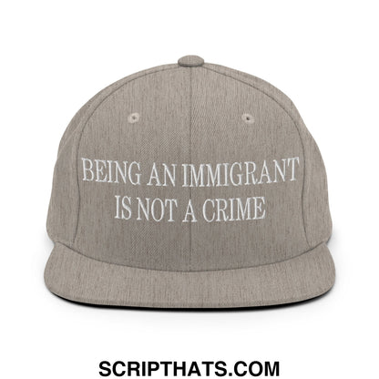 Gray snapback hat with white embroidered text being an immigrant is not a crime on flat bill brim