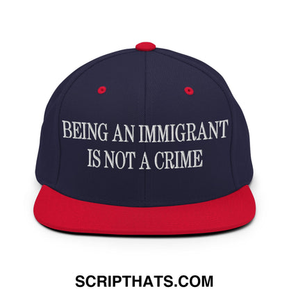 Navy blue and red snapback hat with white embroidered text being an immigrant is not a crime on flat bill brim