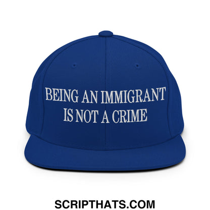 Royal blue snapback hat with white embroidered text being an immigrant is not a crime flat bill brim design