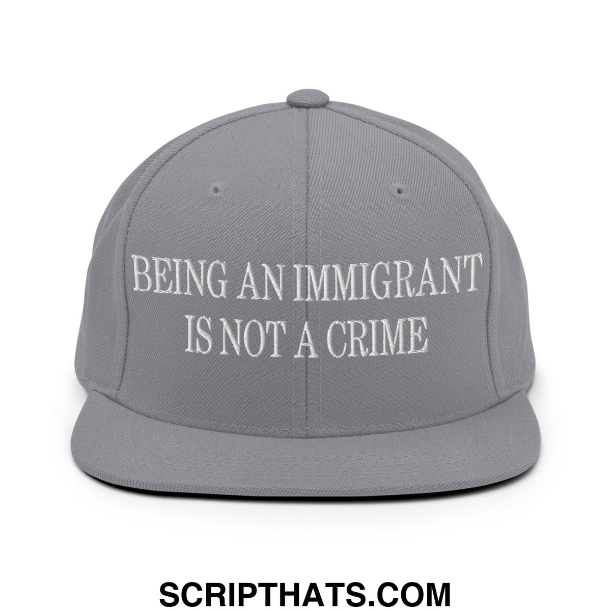 Gray flat bill brim snapback hat with white embroidered text being an immigrant is not a crime on front panel