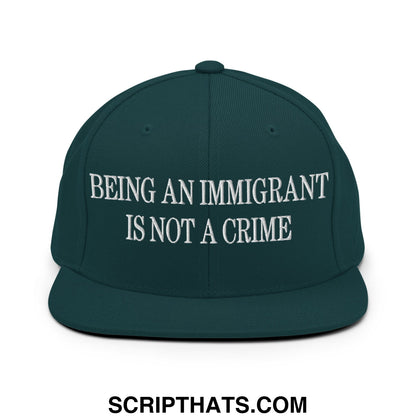 Dark green snapback hat with white embroidered text being an immigrant is not a crime on flat bill brim