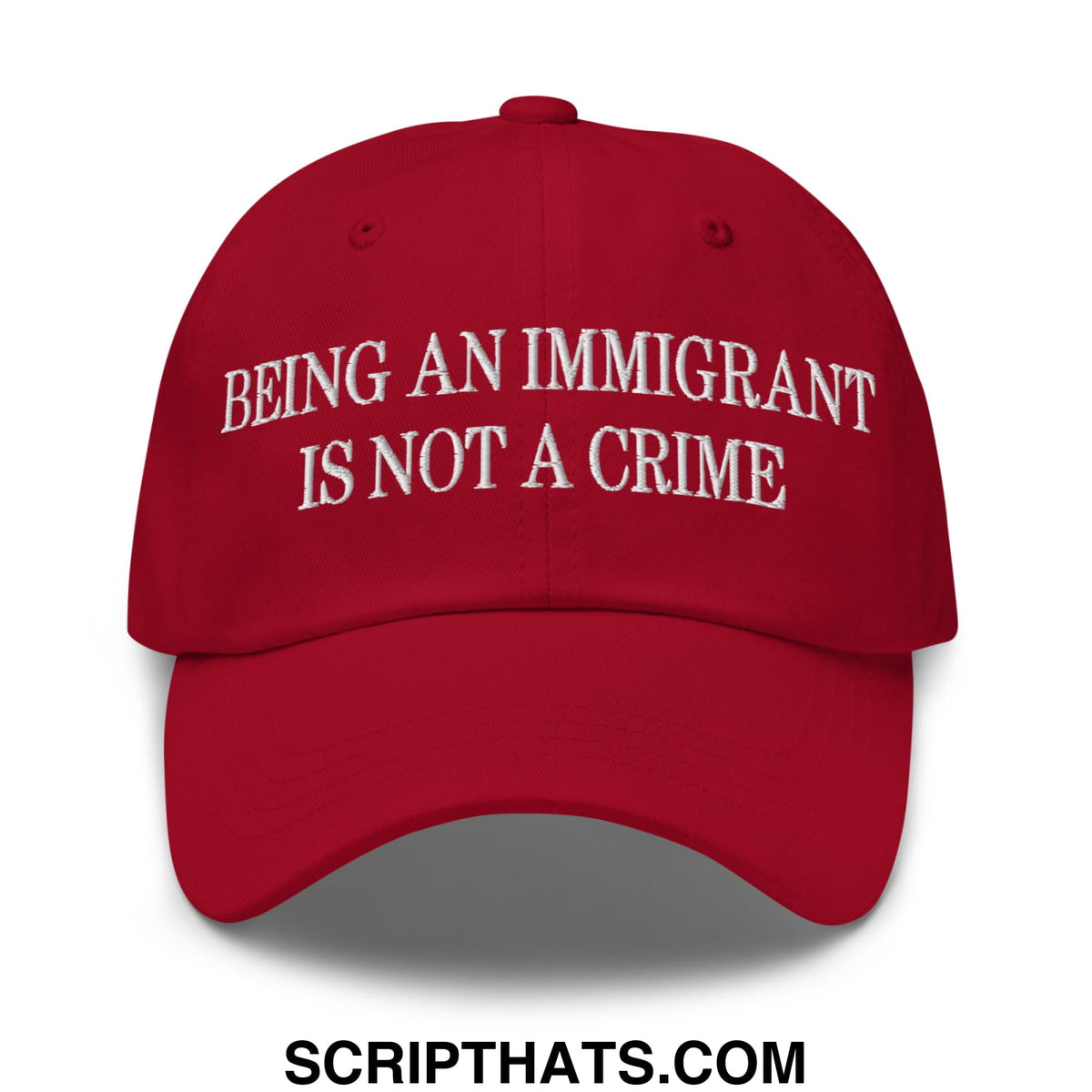 Red embroidered unstructured dad hat with white being an immigrant is not a crime text on front panel