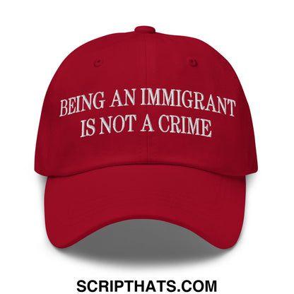 Red embroidered unstructured dad hat with white being an immigrant is not a crime text on front panel