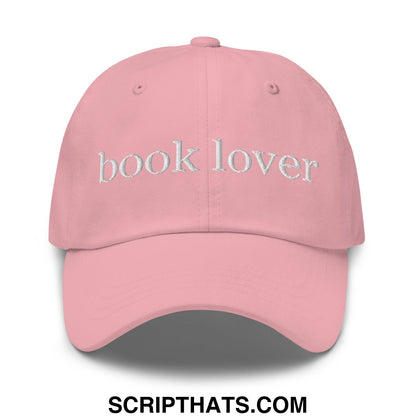 A soft pink unstructured dad hat with book lover embroidered in white thread on the front