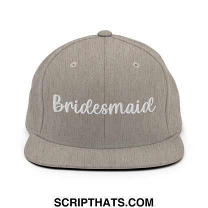 A gray heathered flat bill snapback hat with bridesmaid embroidered in white script on the front