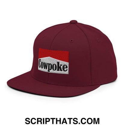 Maroon snapback cap with flat bill featuring a rectangular embroidered patch saying cowpoke with red stripe
