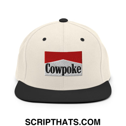 Cream-colored snapback hat with black flat bill brim and embroidered cowpoke logo in red silver and black