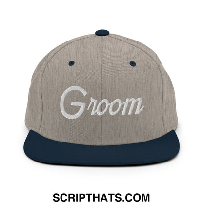 A gray and navy blue snapback hat with groom embroidered in white script on the front flat bill brim