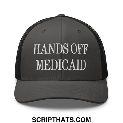 Dark gray mesh trucker hat with white embroidered hands off medicaid text across the front panel