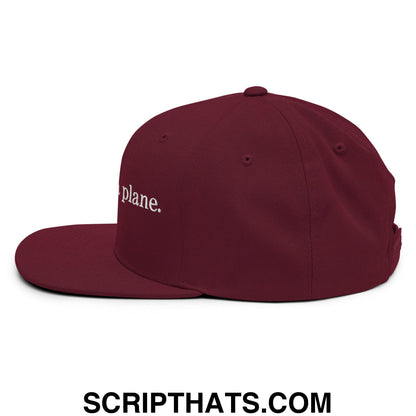 Maroon flat bill snapback cap with white embroidered text plane featuring adjustable strap for casual wear