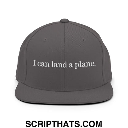 Dark gray snapback cap with white embroidered text reading i can land a plane flat bill brim design