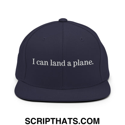 Navy blue snapback cap with white embroidered i can land a plane text and flat bill brim design