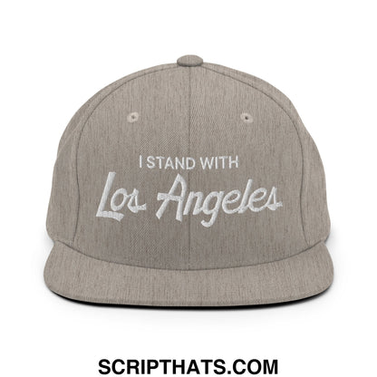 A gray snapback hat with white embroidered i stand with los angeles script text and flat brim design