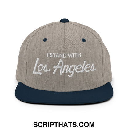 A gray and navy blue snapback hat with i stand with Los Angeles embroidered in white script on the front