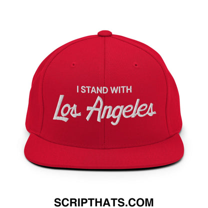 Red snapback cap with white embroidered i stand with los angeles text featuring a flat bill brim and vintage sports script design