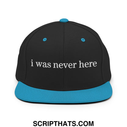 Black snapback cap with teal brim and button featuring white embroidered text i was never here on front panel