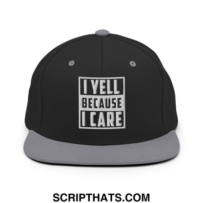 Black snapback hat with gray flat bill brim and white embroidered i yell because i care patch in bold block letters