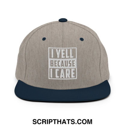 Beige and navy blue snapback hat with white embroidered i yell because i care text and rectangular border on flat bill brim