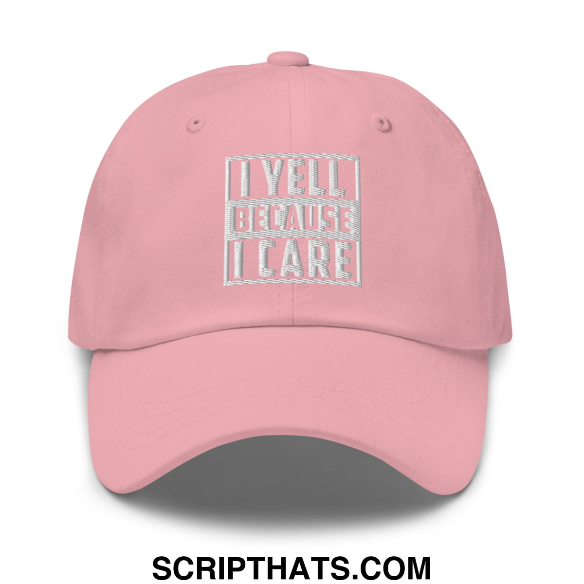 A soft pink unstructured dad hat with white embroidered i yell because i care phrase in a rectangular design