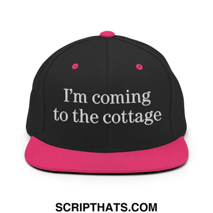 Black snapback hat with a vibrant pink brim and white embroidered im coming to the cottage text on the front