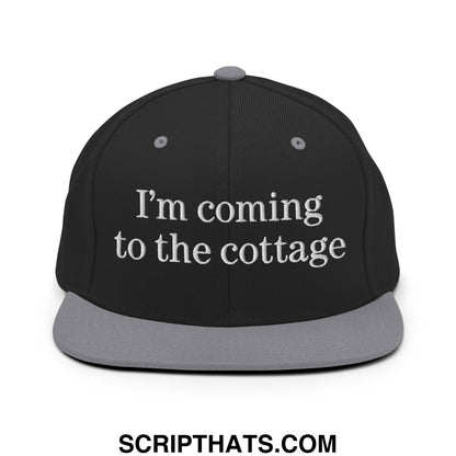 Black snapback cap with gray brim and white embroidered text saying im coming to the cottage flat bill brim hat