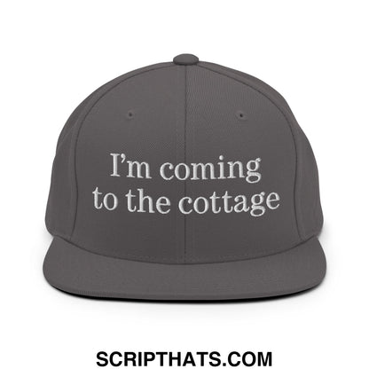 Gray snapback cap with white embroidered text reading im coming to the cottage on flat bill brim