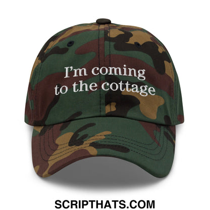 A camouflage-patterned unstructured dad hat with white embroidered text saying im coming to the cottage