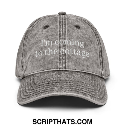 A faded gray unstructured denim dad hat with white embroidered text saying i’m coming to the cottage