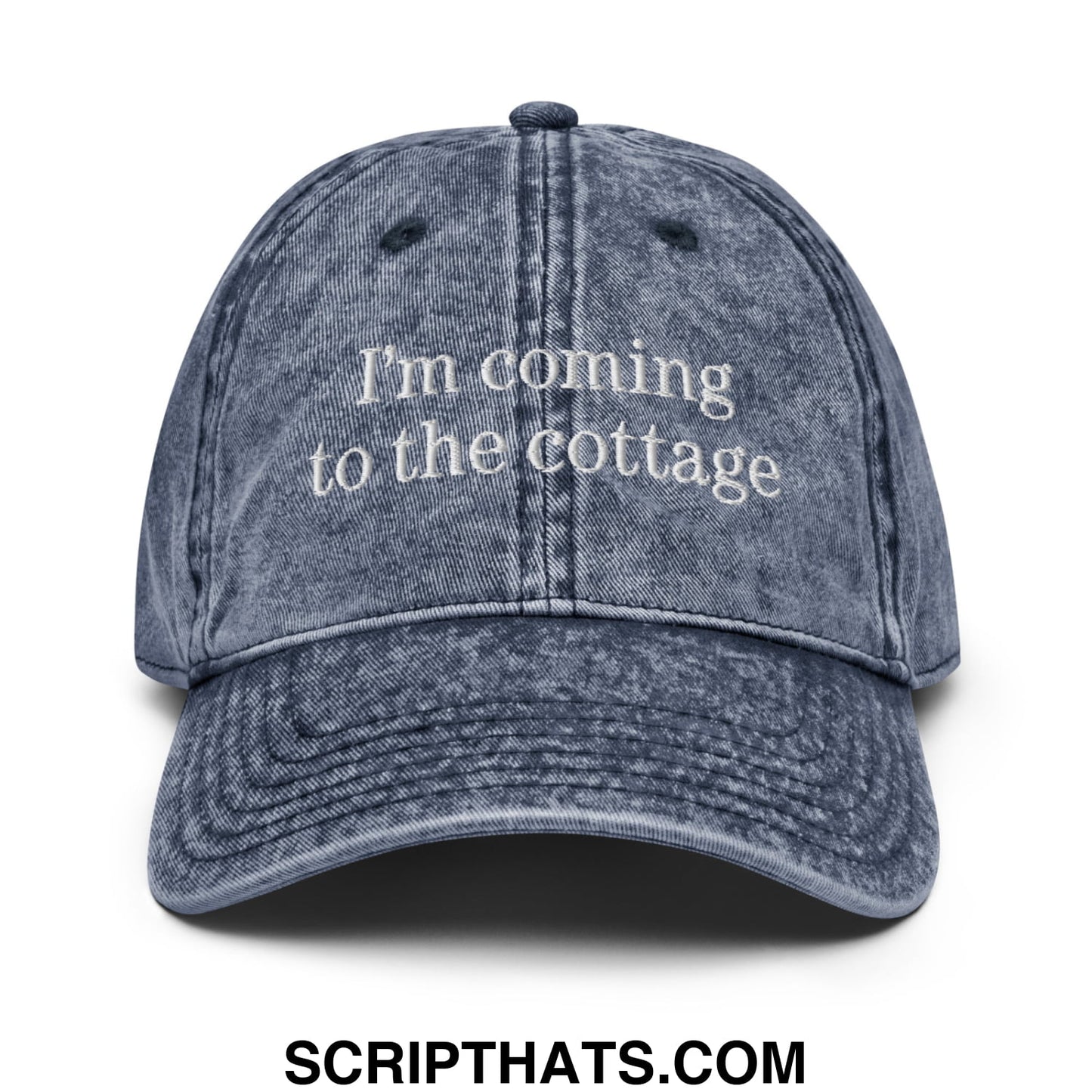 A faded blue denim dad hat with white embroidered saying Im coming to the cottage for casual wear