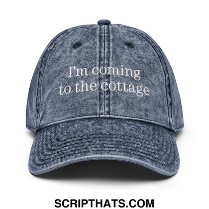 A faded blue denim dad hat with white embroidered saying Im coming to the cottage for casual wear