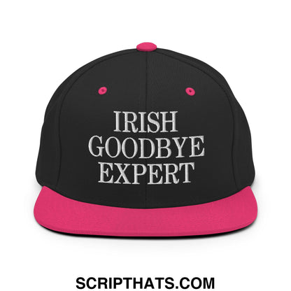 Black snapback cap with flat bill, vibrant pink brim and button, white embroidered irish goodbye expert text