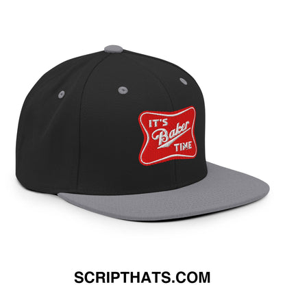 Black and gray snapback hat with a red embroidered patch reading its baker time in white script on the front