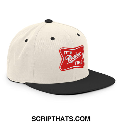 Cream-colored snapback hat with black brim and embroidered red patch reading its baker time in white script