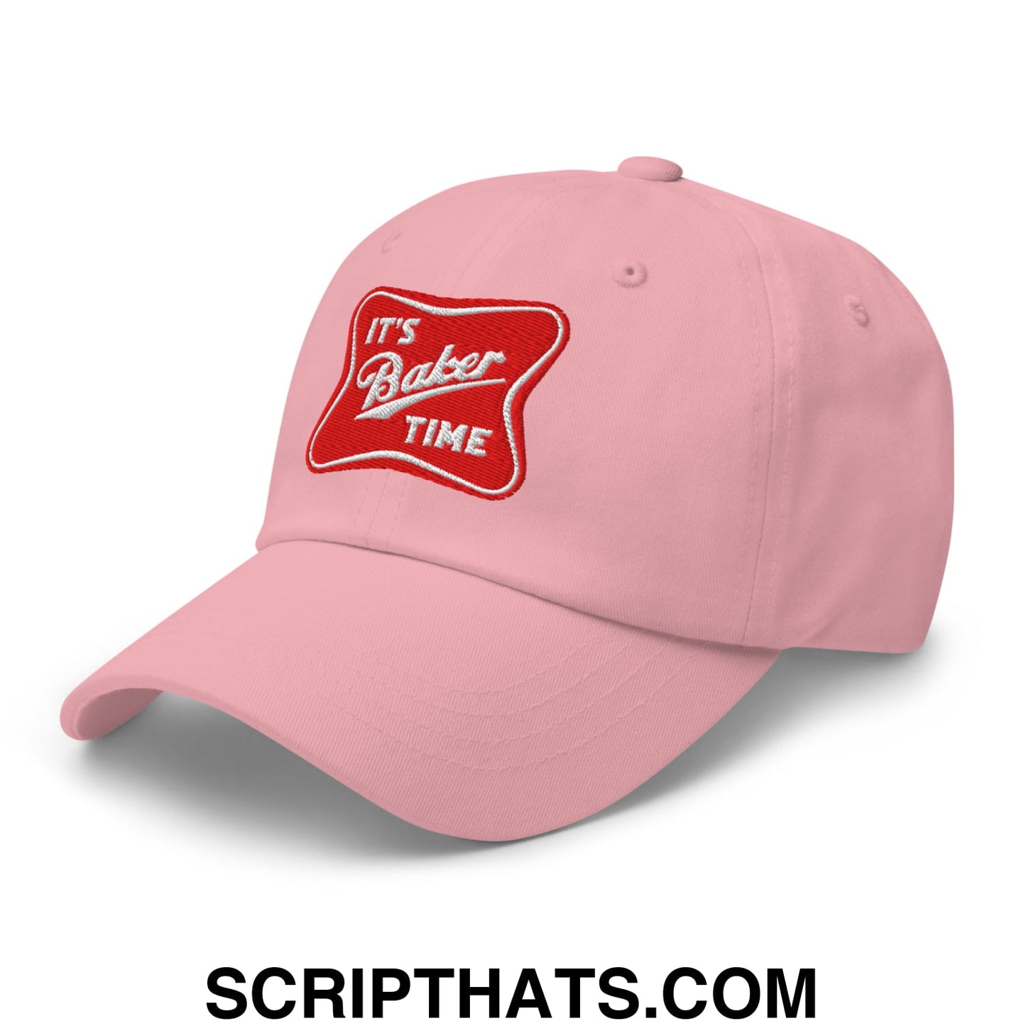 A soft pink unstructured dad hat with a red embroidered patch that says its baker time in white cursive script