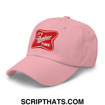 A soft pink unstructured dad hat with a red embroidered patch that says its baker time in white cursive script