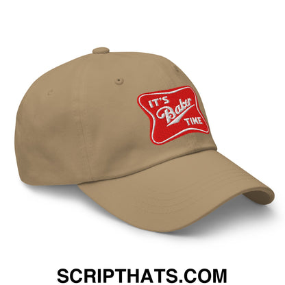 Beige unstructured dad hat with red embroidered patch reading it’s baker time in white cursive text