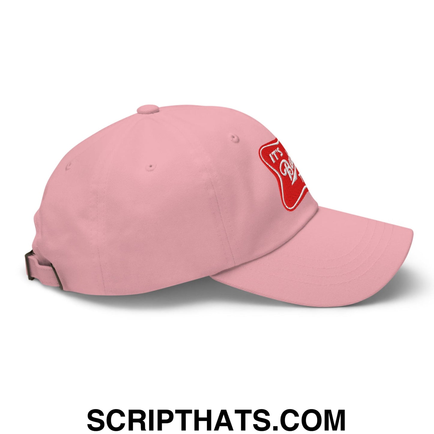 A soft pink unstructured dad hat with red embroidered patch on the side titled its baker time embroidered cap