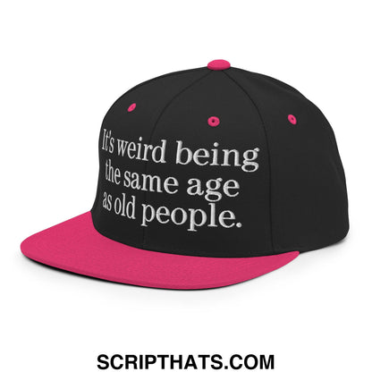 Black and pink flat bill brim snapback hat with white embroidered text reading its weird being the same age as old people
