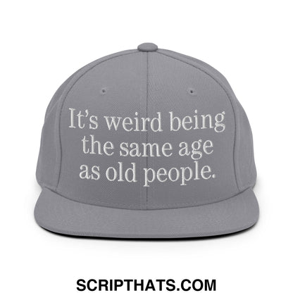 Gray snapback hat with white embroidered text its weird being the same age as old people flat bill brim style