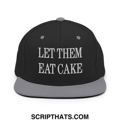 Black snapback cap with gray flat bill and white embroidered let them eat cake text on front panel