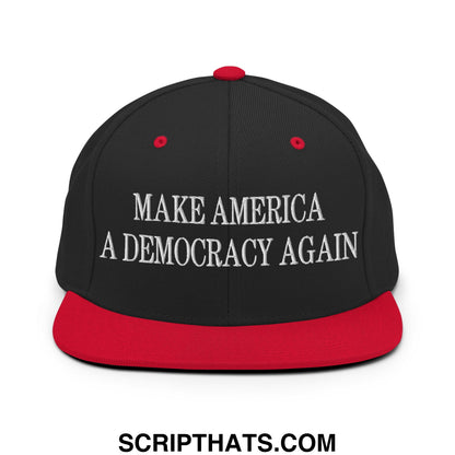 Black snapback cap with red brim and button featuring white embroidered text make america a democracy again