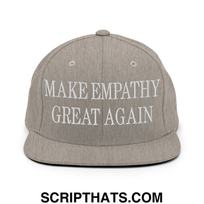 A gray snapback hat with white embroidered text reading make empathy great again flat bill brim design