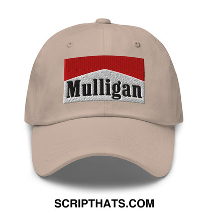 Beige unstructured golf dad hat with embroidered rectangular patch featuring red top silver middle and black mulligan lettering